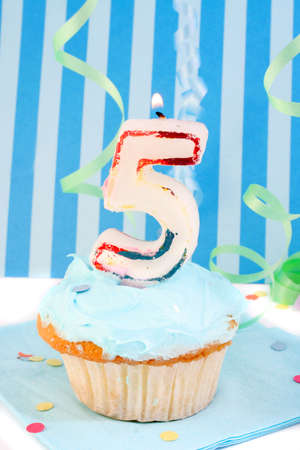  boy's fifth birthday cupcake with blue frosting and  decorative background の写真素材