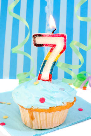  boy's seventh birthday cupcake with blue frosting and  decorative background の写真素材