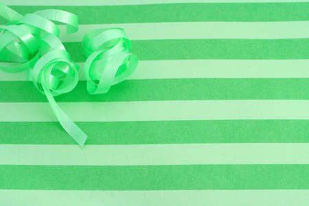 green striped background with curled ribbon which could be the top of a present box or wrapping paperの写真素材