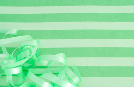 green striped background with curled ribbon which could be the top of a present box or wrapping paperの写真素材