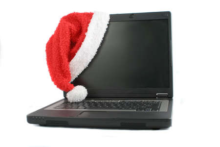 mobile laptop computer with santa christmas hat hanging off the screenの写真素材