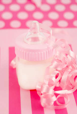 a pink  bottle with milk and celebratory ribbon suitable for new  on decorative pink backgroundの写真素材
