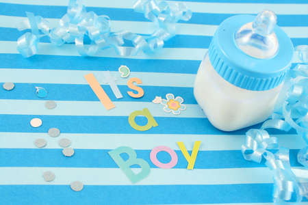 a blue baby bottle with milk and celebratory it's a boy text and  ribbon suitable for new babyの写真素材