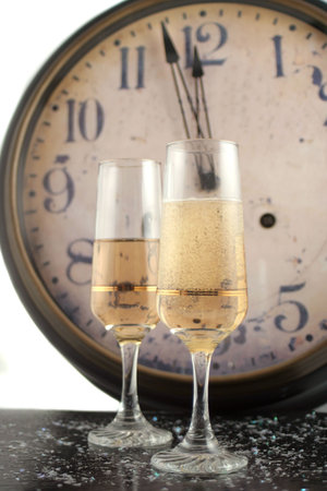 champagne in glasses with new years countdown vintage clock in the backgroundの写真素材
