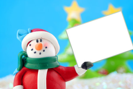 fantasy wonderland scene with  snowman holding a blank white sign with christmas trees in the backgroundの写真素材
