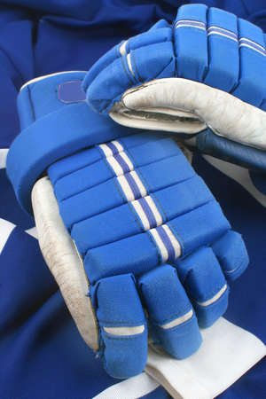 professional protective hockey gloves protecting hands and fingers on top of a dark blue and white jerseyの写真素材
