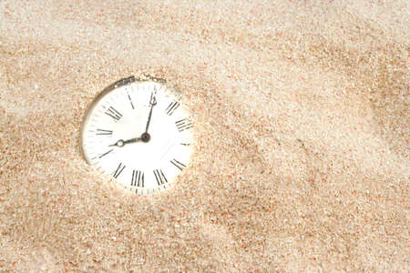 pocket watch in the sand with the concept of sand of time, good for a backgroundの写真素材
