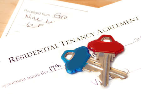 residential tenancy agreement document with blue and red keys on top and a rental cheque underneathの写真素材