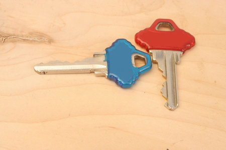 red and blue house keys laying on a wood background