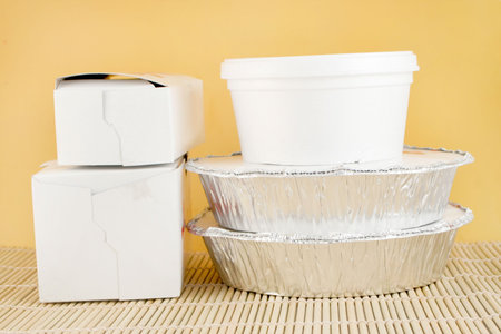 chinese food delivery or takeout aluminum covered containers and cardboard boxes on bamboo placemat の写真素材