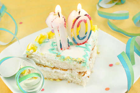 slice of tenth birthday cake with lit candle, confetti, and ribbon (shallow depth of field)の写真素材