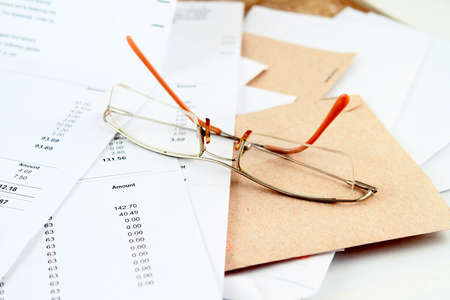 Different bills to be paid and envelopes with eyeglasses on top for prompt paymentsの写真素材