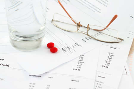 Different bills to be paid. envelopes and eyeglasses with red pills, and water to soothe the headache of paying billsの写真素材