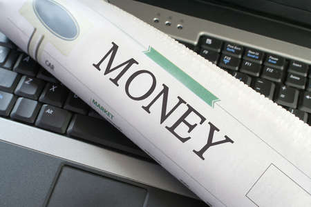 Money section of the newspaper laying on a laptopの写真素材