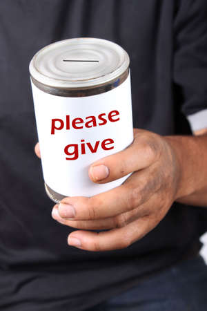 Homeless man with dirty hands holds a tin can that says please give .... asking for change の写真素材