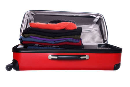 Clothes piled up while packing a hard shell red suitcaseの写真素材