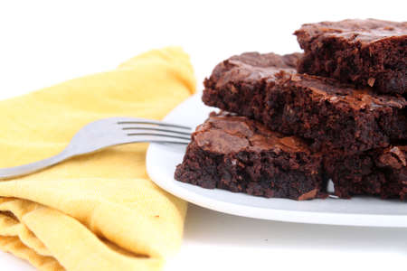 Pile of chocolate fudge brownies on a plate with a white  background (short depth of field)の写真素材