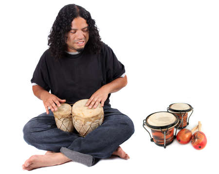 Funky long haired ethnic African American and Native Indian male playing bongo drums on a white background with other latin instruments to the sideの写真素材