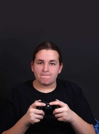 Teenager holding a video game controller with intense expression on his face (shallow depth of field)の写真素材