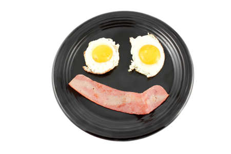 Bacon and fried eggs for breakfast in the shape of a happy face, isolated on a white backgroundの写真素材