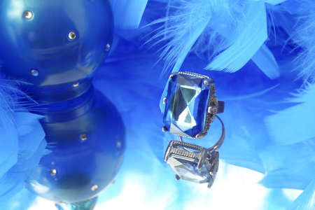glamorous diamond ring on vanity mirror with a blue  feather boa and perfume bottle in the backgroundの写真素材
