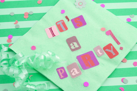 cut out letters spelling it's a party on light green napkins with curled ribbons and confetti, great...
