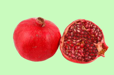 Closeup of ripe, and fresh cut   pomegranate isolated on a green backgroundの写真素材