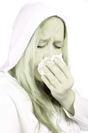 Woman wearing a hooded sweater holds a tissue due to sniffles or sneezing with high key green color effectの写真素材