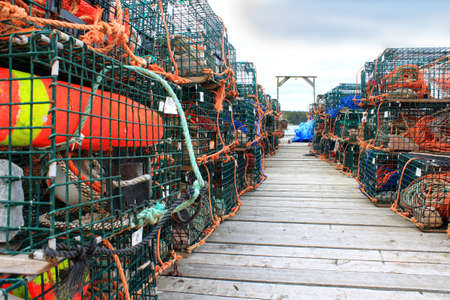 Traps for lobsters and other crustaceans with colorful buoys on a wooden fishermen's wharfの写真素材