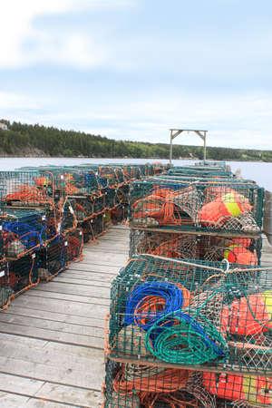 Traps for lobsters and other crustaceans with colorful buoys on a wooden fishermen's wharfの写真素材