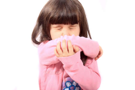 Little sick girl sneezing onto her sleeve because of sickness or allergiesの写真素材