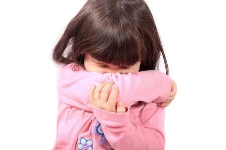 Little sick girl sneezing onto her sleeve because of sickness or allergiesの写真素材