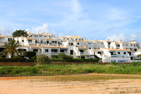 Beachside white washed houses on a street in the Algarve showing typical chimneys from southern Portugalの写真素材