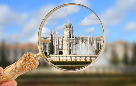 Magnifying glass focusing in on The Mosteiro or monastery dos Jeronimos displaying Manueline architecture with fountain from Praca do Imperio gardens, Portugalのeditorial素材