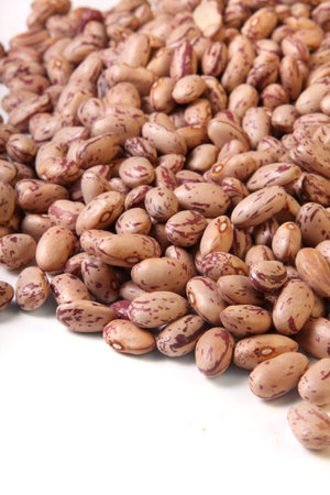 A Pile of Romano Beans also known as cranberry beans, spilled out over a white background