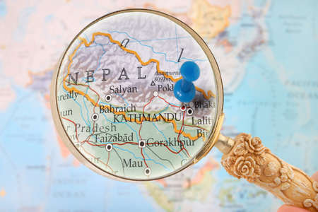 Looking in on Kathmandu, Nepal with a magnifying glass and a blurred map of Asia in the backgroundの写真素材