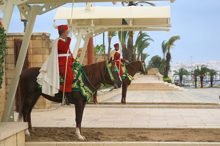 RABAT. MOROCCO - FEBRUARY 20, 2016: Mounted  Royal guard at entrance of the Mausoleum of Mohammed V on horseback wearing traditional attire of red in the winter.のeditorial素材