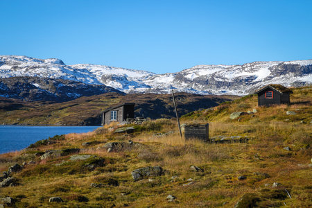 Lake with snow covered mountains and grass roofed shacks  in the Telemark region Norway, Scandinaviaの写真素材