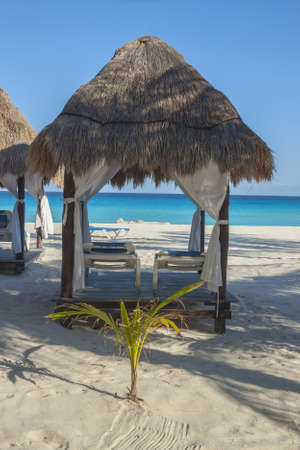 Loungers under hut canopy on a Caribbean beach in Cancun Mexico,の写真素材