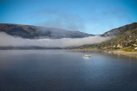Quiet lake in rural Norway with fog patch on beautiful calm lakeの写真素材
