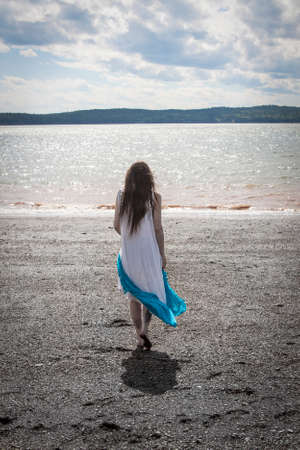 Woman strolling along Black Beach near Lorneville, New Brunswick, Atlantic Canada on the Bay of fundyの写真素材