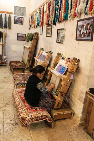 Cappadocia, Turkey - 2016-02-20 : Woman weaves a colorful mat in a warehouse in Cappadocia, Turkeyのeditorial素材