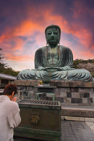 Woman praying and wishing at The Great Buddha at Kamakura, Japan at sunsetのeditorial素材