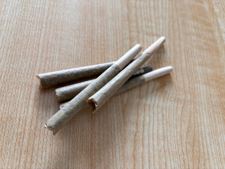 A couple of grams of Rolled marijuana flower joints on top of a wooden table, pre rolls
