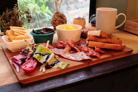 Bacon sausages vegetable and eggs served on wooden plateの写真素材