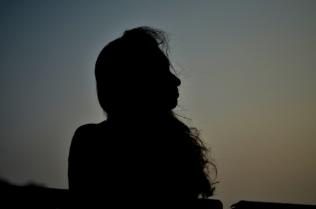 Lonely girl silhouette under big black skyの写真素材