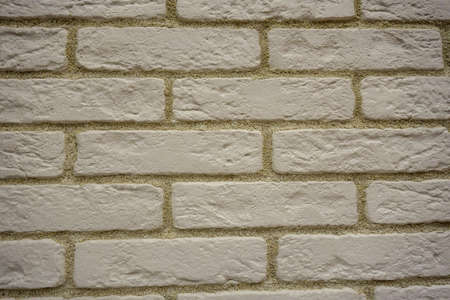 Wall of white uneven bricks with a yellowish seam.の写真素材
