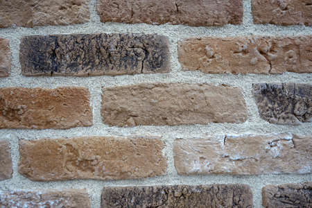 wall made of old bricks of various shades with a white seam.の写真素材