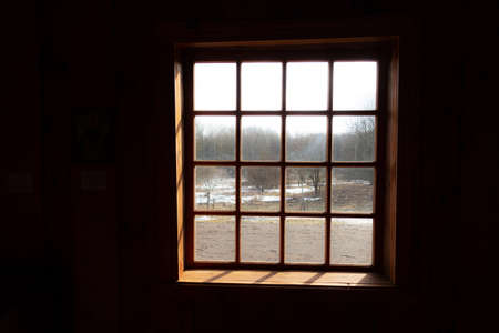 view from a dark room through a lattice window on the March forestの写真素材