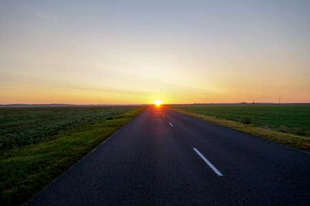 The road leading straight to the rising sun at dawnの写真素材